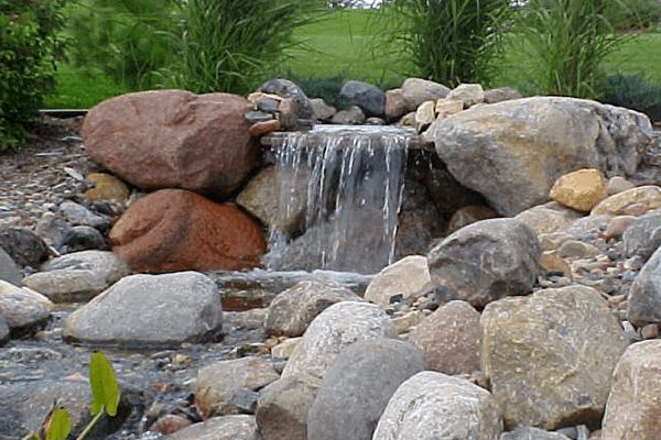A Water Fall is Prominent in This Lovely Backyard Rock Garden With a Pond